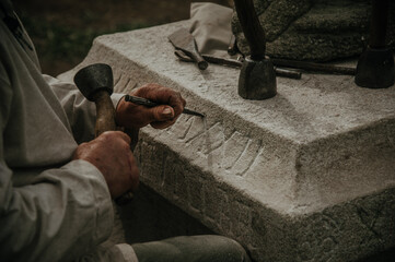 A person meticulously carving Latin text on a stone column, showcasing traditional craftsmanship...