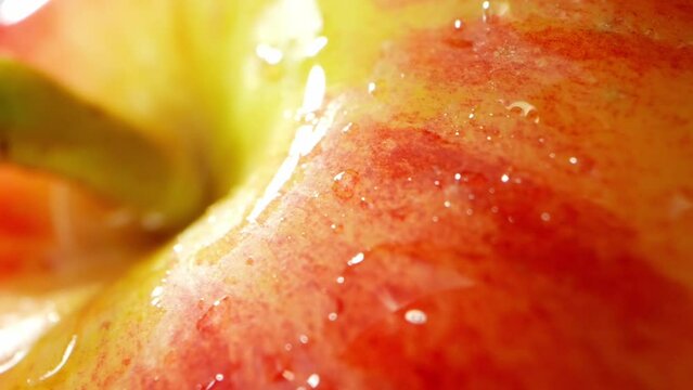 In a mesmerizing macro video, the Jazz apple glistens with droplets of water, each one capturing the light and reflecting a world of vibrant colors. Fruit concept. Apple background. 4K UHD
