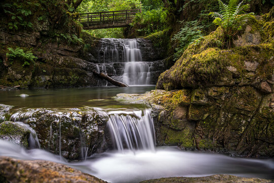 The Sychryd Cascades or Sgydau Sychryd Falls with wooden bridge in the Waterfall Country near the Dinas Rock, Pontneddfechan, Brecon Beacons National Park, South Wales, UK. Long exposure water.