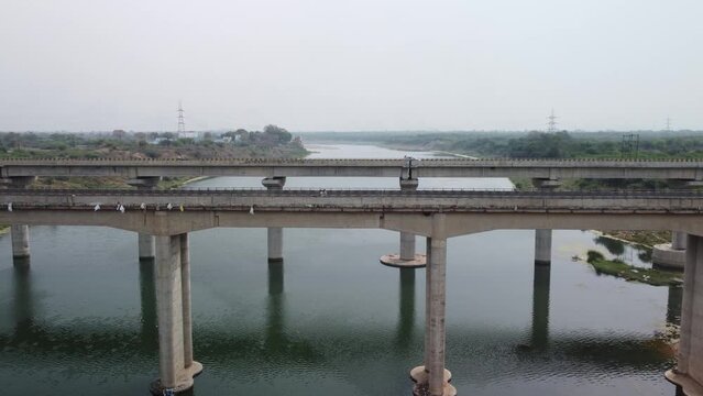 Highway bridge built over the river basin in the Indian rural terrain, slow motion, Drone shot