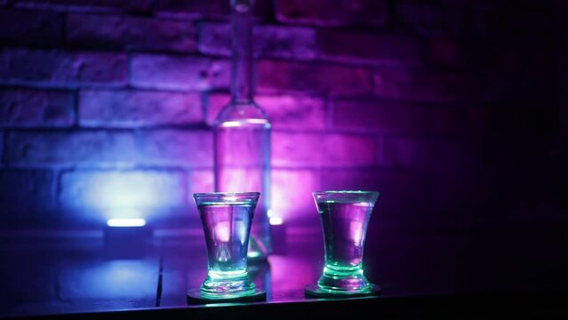Cold vodka glass on a dark background in the neon light or glasses of russian vodka on bar background. selective focus