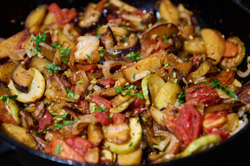 Food background with vegetable stew, ratatouille of roasted veggies sprinkled with fresh herbs, in...