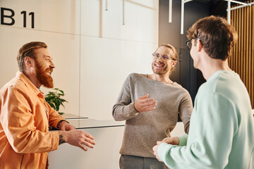 motivated and excited business partners in stylish casual clothes meeting in hall of contemporary...