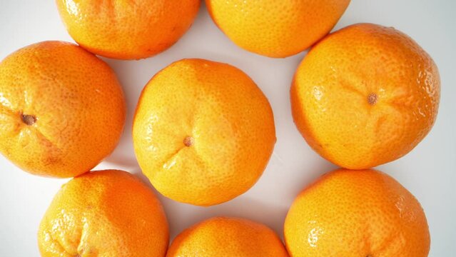 A group of plump oranges, their vibrant citrus hues gleaming under the sunlight. Each round fruit is perfectly spherical, adorned with a dimpled, textured skin. Fruit concept. Orange background. 4K
