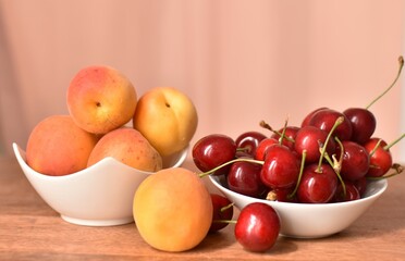 ripe apricots and cherries in white cups against the backdrop of pink curtains