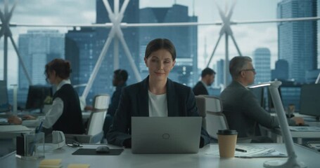 Lay Offs, Reductions and Stress Concept: Female Project Manager working On Laptop In Skyscraper Office In Downtown. Businesswoman Looking at Camera. Dramatic Blue colograde