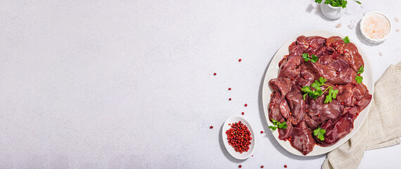 Raw chicken liver on stone background. Fresh ingredients ready for cooking, parsley, red pepper