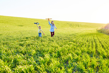 Cheerful and happy children play in the field and imagine themselves to be pilots on a sunny summer day. Kids dreams of flying and aviation.