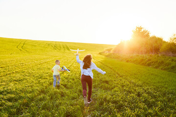 Cheerful and happy children play in the field and imagine themselves to be pilots on a sunny summer day. Kids dreams of flying and aviation.