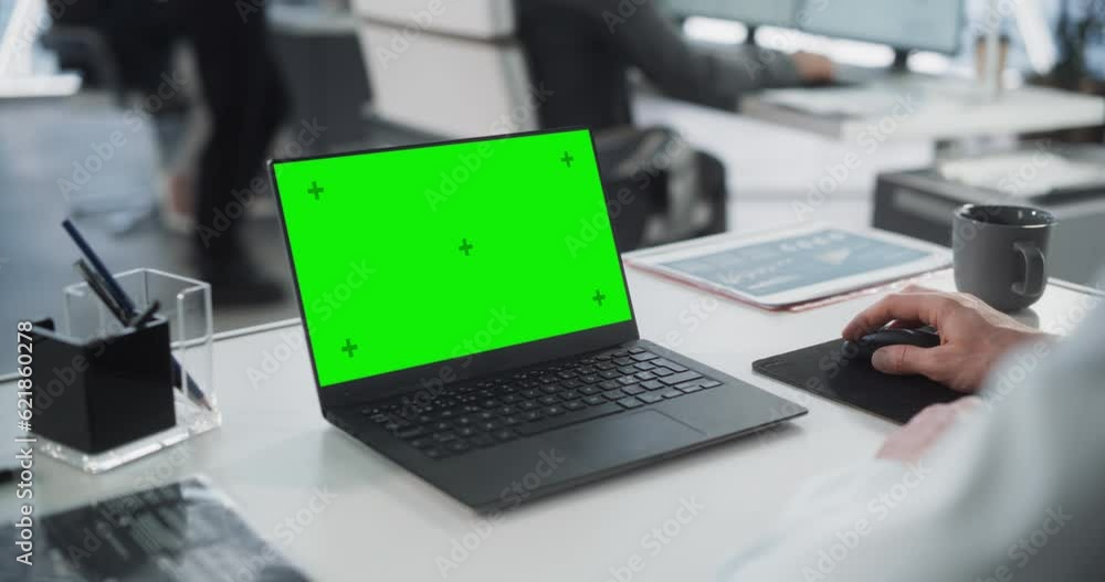 Poster successful caucasian businessman sitting at desk working on green screen laptop computer in office. 