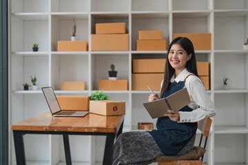 Fototapeta na wymiar Asian woman online store business owner, online shop owner working from home, products for sale on and accepting orders and packing products for customers with courier service
