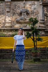 Pretty Asian tourists woman wearing beautiful hand-woven clothes dyed with indigo and mud-fermented natural colors modern Thai traditional dress costumes are popular in ancient temple Thailand.