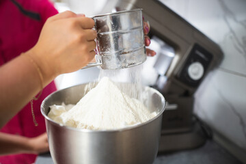 the cook sifts flour through a sieve to knead the dough
