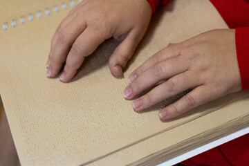 close-up of a woman's hand reading a braille book