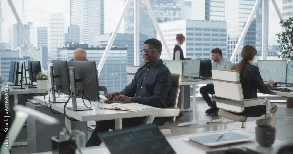 Poster Focused African American Male Data Analyst Typing On Desktop Computer In Diverse Corporate Office With Megapolis Window View. Professional Balck Man Working In Consulting Company With Colleagues.