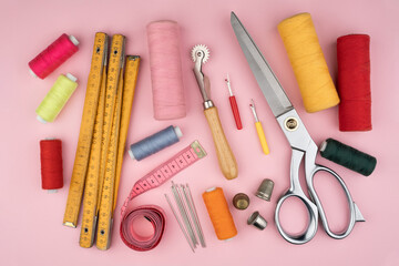 various tailor accessories and tools for tailoring on a pink background