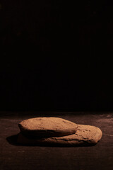 Brown stone podium display on black background, mockup. Decorative textured stand for beauty...