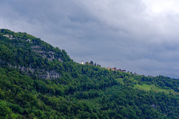Fototapeta na wymiar Scenic landscape with rock, cliff and woodland with mountain village Seelisberg at lakeshore of Lake Uri on a cloudy spring day. Photo taken May 18th, 2023, Seelisberg, Switzerland.