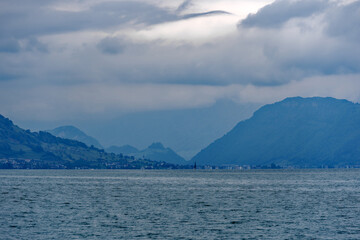 Scenic view of Lake Lucerne with mountain panorama and woolland in the background on a cloudy spring day. Photo taken May 18th, 2023, Treib, Switzerland.