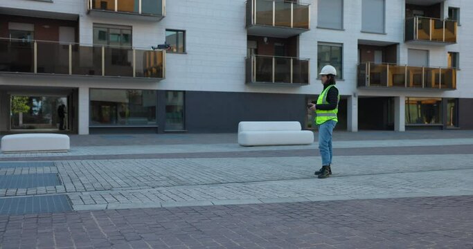 Engineer in safety vest and helmet controls drone for photogrammetry by flying it off ground