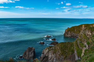 dramatic coast edge with cliff rocks and blue sea and skies holiday summer