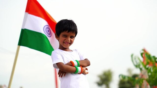 Cute little boy holding Indian flag in his hands and smiling. Celebrating Independence day or Republic day in India. Kid showing pride of Tiranga