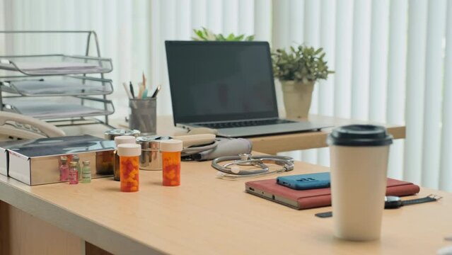 Medium shot of doctors workplace with pills, coffee, laptop, smartphone and medical equipment on desk