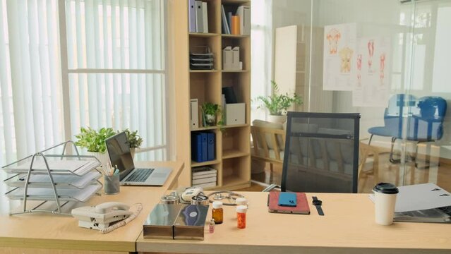 Wide shot of doctors workplace with piils, laptop, smartphone, smartwatch and coffee at desk