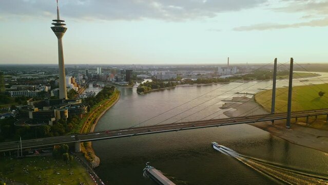 Aerial drone footage of Dusseldorf city, skyline with bridge and Rheinturm over river Rhine at sunset.