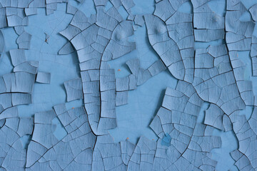 Blue peeling paint on the wall. Old concrete wall with cracked flaking paint. Weathered rough...
