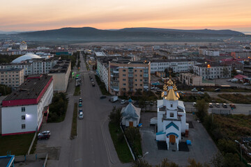 Aerial view of the city at dawn. Morning cityscape. Top view of the church, buildings and an empty street. Church of Saint John the Baptist, city of Magadan, Magadan region, Siberia, Far East Russia.