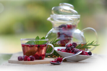 Frischer Eistee in einer Glastasse mit gefrorenen roten Früchten dekoriert - 621886061