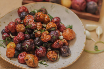 young colored potatoes baked whole in the oven on a plate close-up, appetizing potatoes