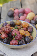 young colored potatoes baked whole in the oven on a plate close-up, appetizing potatoes