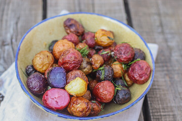 young colored potatoes baked whole in the oven on a plate close-up, appetizing potatoes