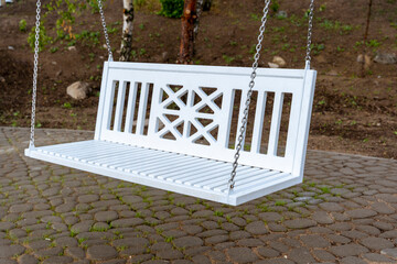 white bench-swing on chains in the park - obrazy, fototapety, plakaty
