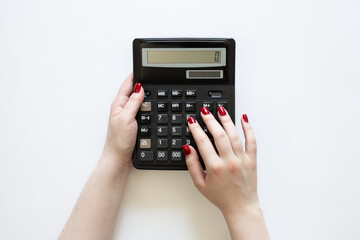 Black calculator in the hands of a woman on a white background, top view.