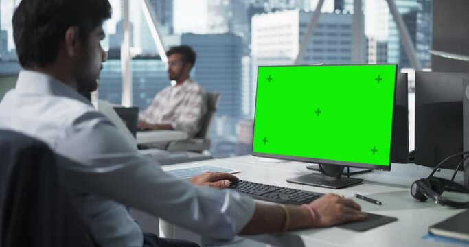 Indian Chief Financial Officer Working on Desktop Computer with Green Screen Mock Up Display. Young South Asian Specialist Analyzing Corporate Banking Account, Researching Investment Opportunities