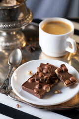 Chocolate with large nuts and a cup of coffee on a metal tray
