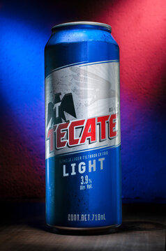Mexicali, Baja California. Mexico. May-01-2020. TECATE Light beer in a can with red and blue lights in the background on a rustic wooden table, as part of marketing image or advertising purposes