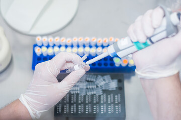 Un scientifique en train de manipuler des prélèvements dans un laboratoire  avec une pipette dans...
