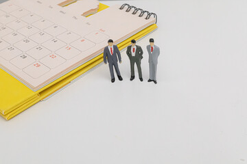 Miniature three people businessman standing on yellow calendar. business and financial concept....