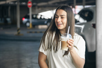 Young woman with a cup of coffee in the parking lot.