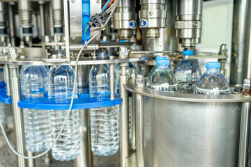Female worker inspecting water bottle on production line in spring water factory