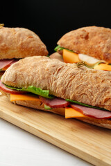 Chiabatta sandwich with ham and cheese on wooden board