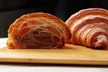 Freshly baked croissant with powdered sugar on wooden board