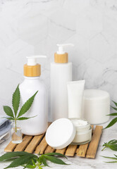 Obraz na płótnie Canvas Opened cream jar with blank lid near green cannabis leaves close up, CBD cosmetic mockup