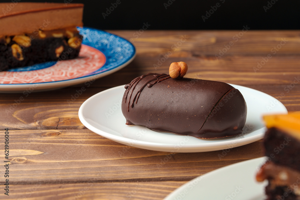 Poster Delicious chocolate cake in white plate on wooden table background