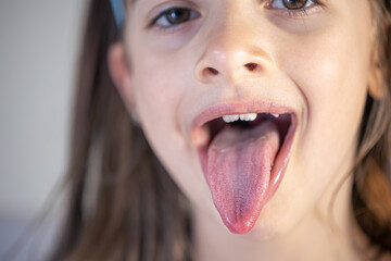 A child girl open her mouth and show her tounge.