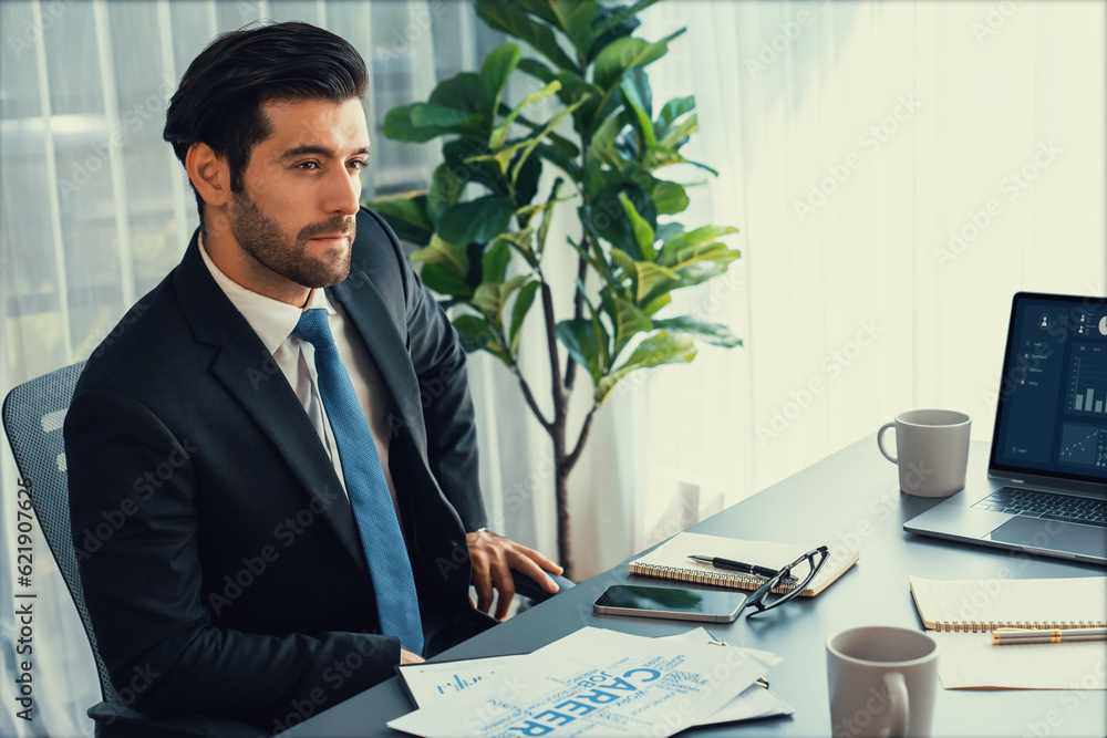 Poster modern professional businessman at modern office desk using laptop to work and write notes. diligent